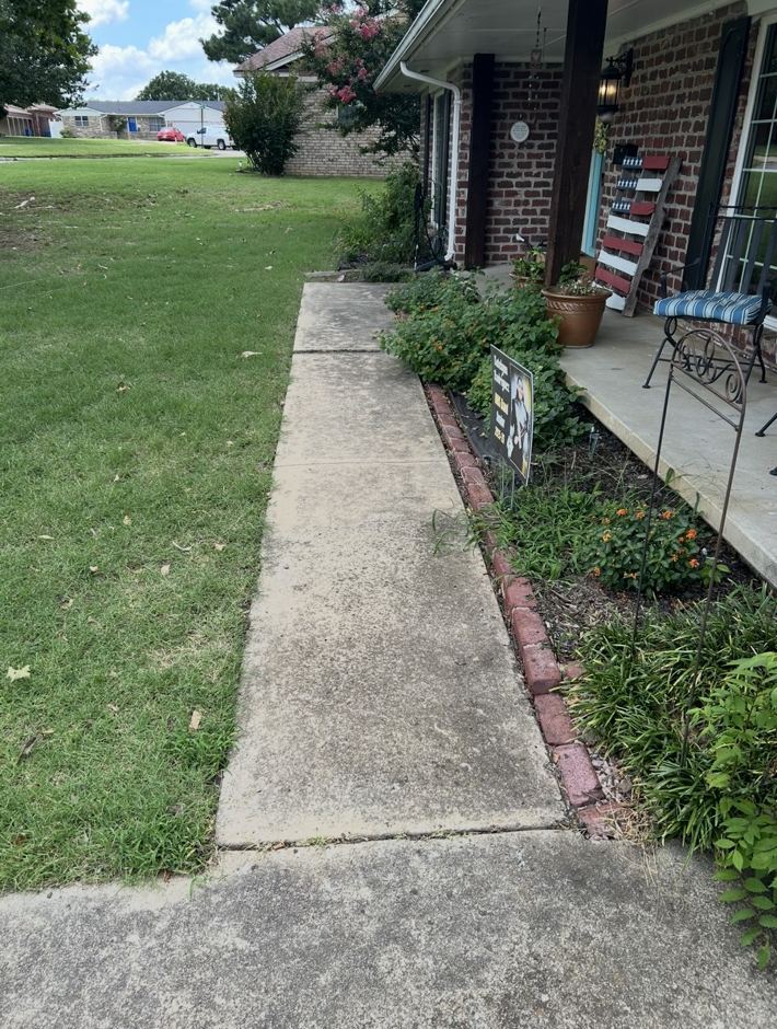 Concrete walkway at a brick home, stained and darkened, before cleaning